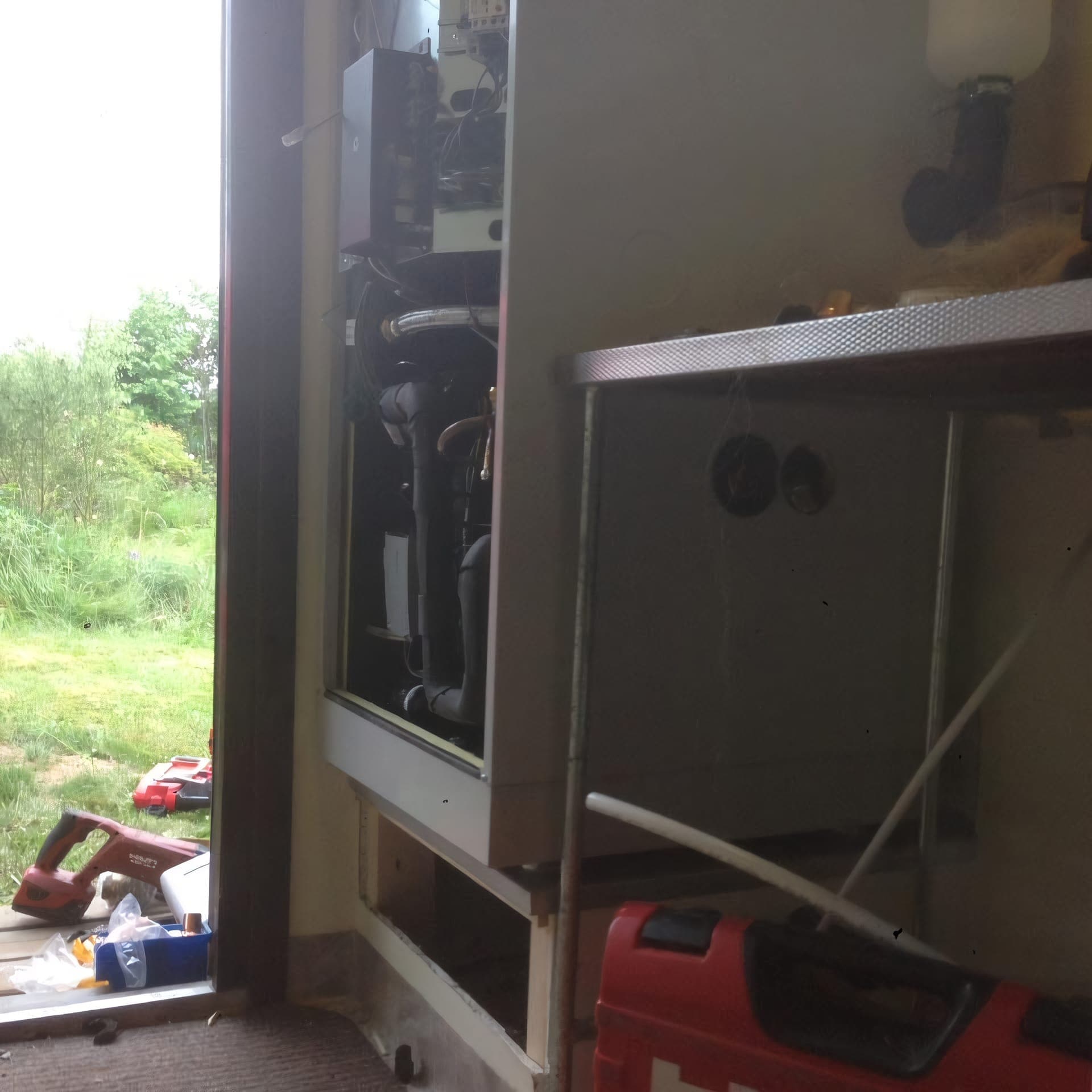 Värmepumpsanläggning som servas inomhus med öppnad enhet och verktyg på golvet.