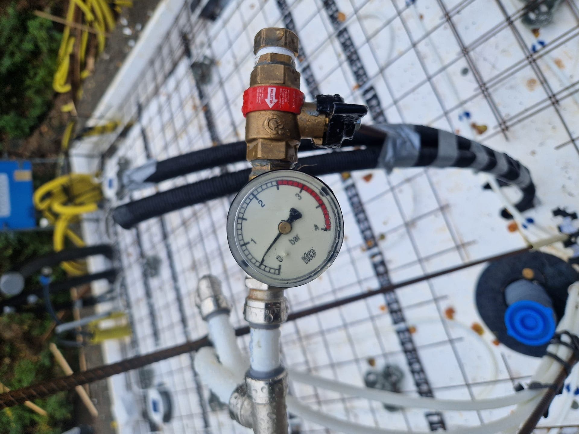 Golvvärmefördelare under installation med manometer och påfyllningsventil.