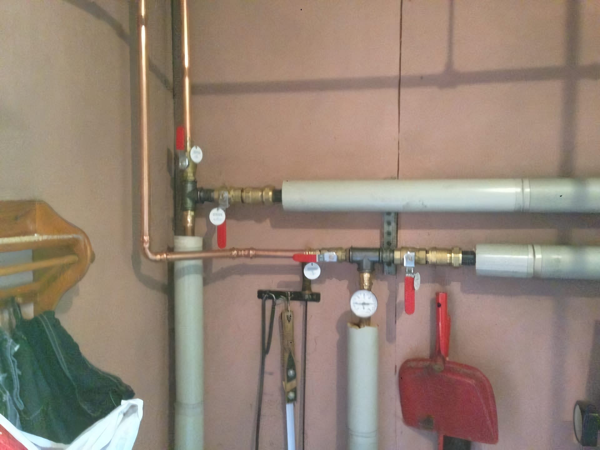 Rörinstallation med koppar- och PEX-rör, avstängningsventiler och manometer i ett pannrum.