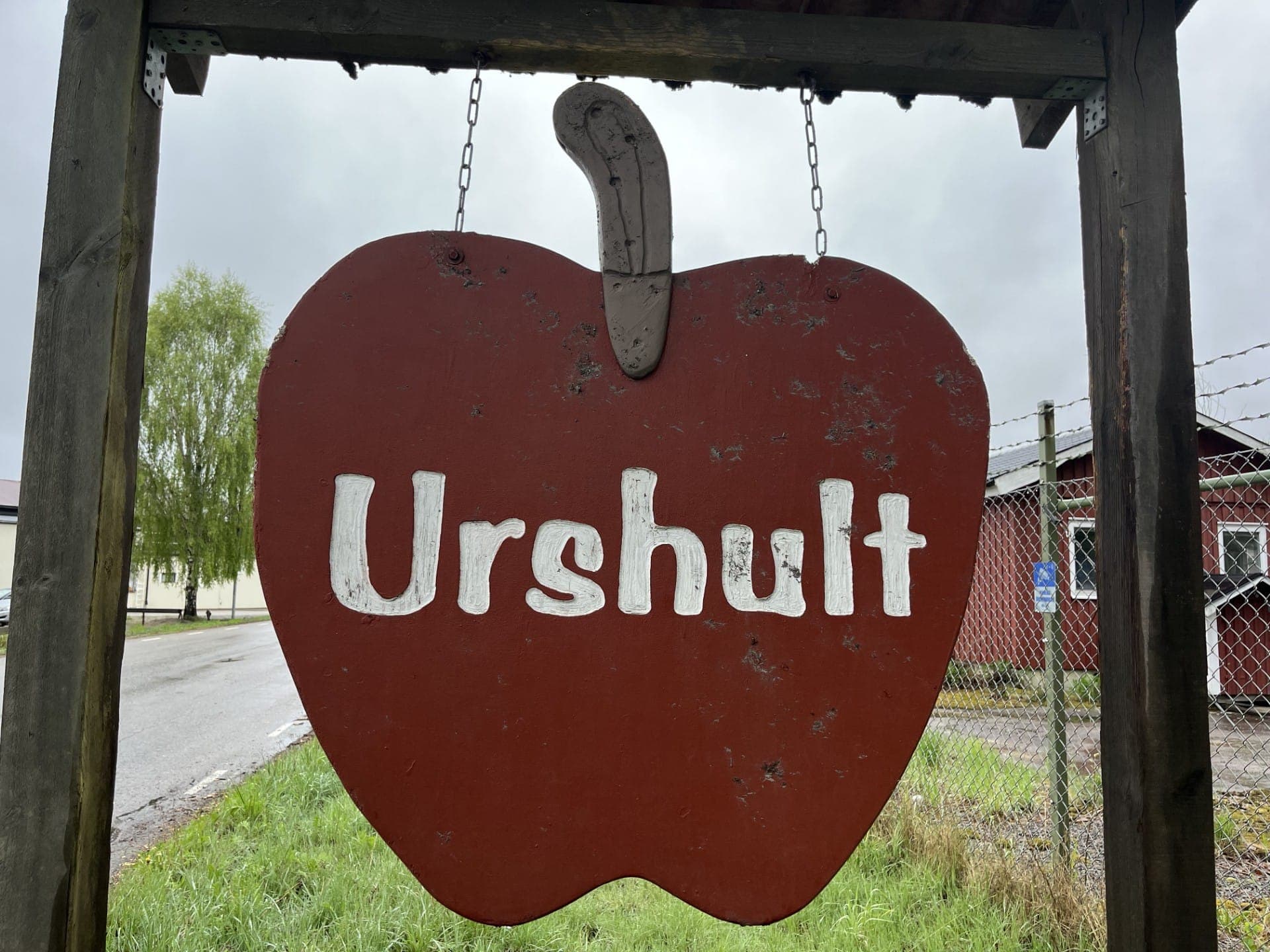 Äppelformad ortsskylt med texten Urshult vid vägen.