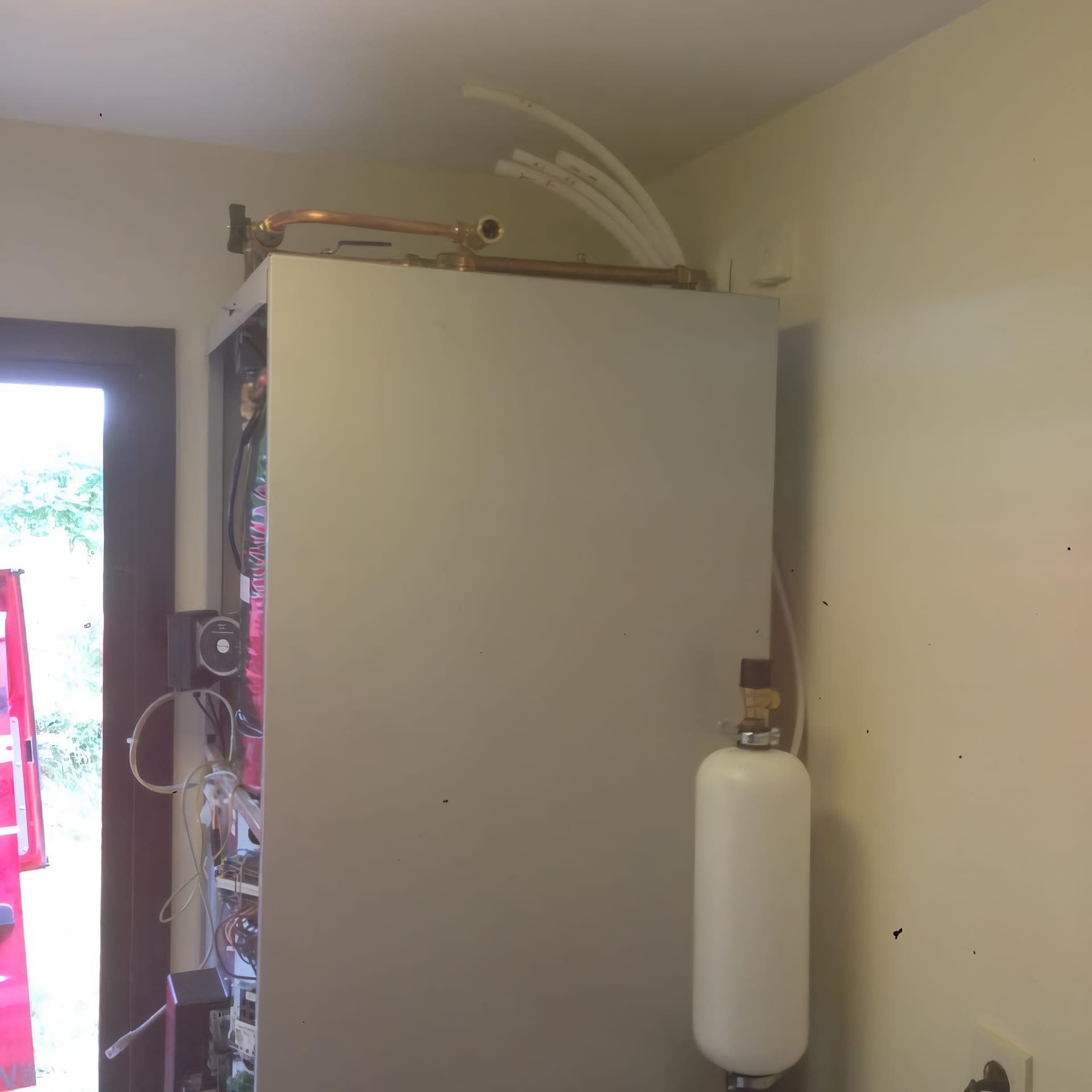 Inomhusinstallation av värmepump med nydragna kopparrör och expansionskärl.